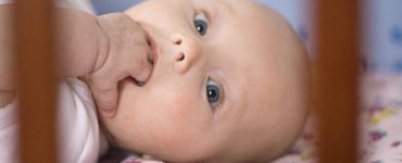 neonato con mani in bocca