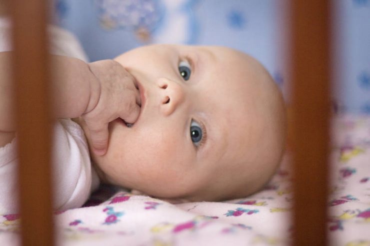 neonato con mani in bocca