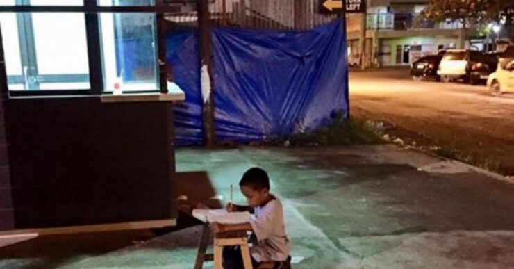 Bambino filippino fa compiti per strada