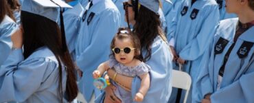 Giovane mamma con la neonata in braccio nel giorno della laurea