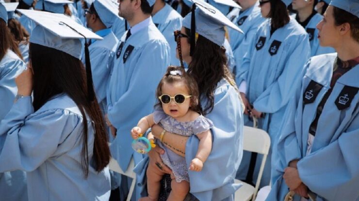 Giovane mamma con la neonata in braccio nel giorno della laurea