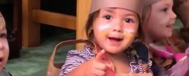Bimba appena adottata indica la sua mamma continuamente alla recita scolastica